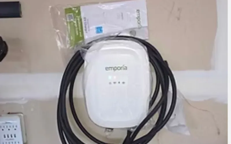 Emporia Level 2 EV charger mounted on a wall with its charging cable coiled