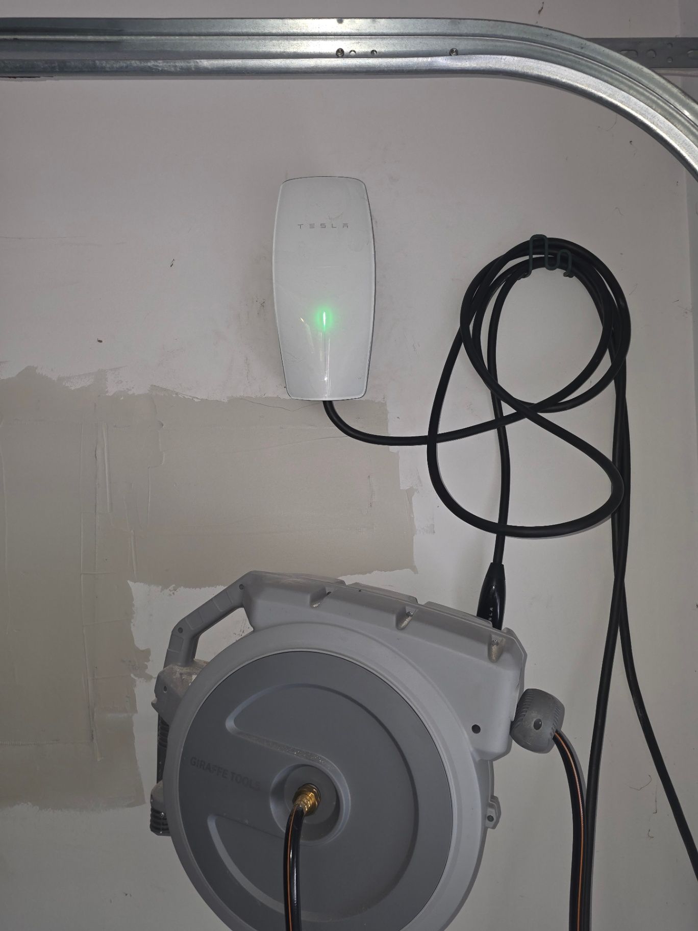 Tesla Universal Wall Connector installed cleanly in a residential garage with adjacent EV charging equipment
