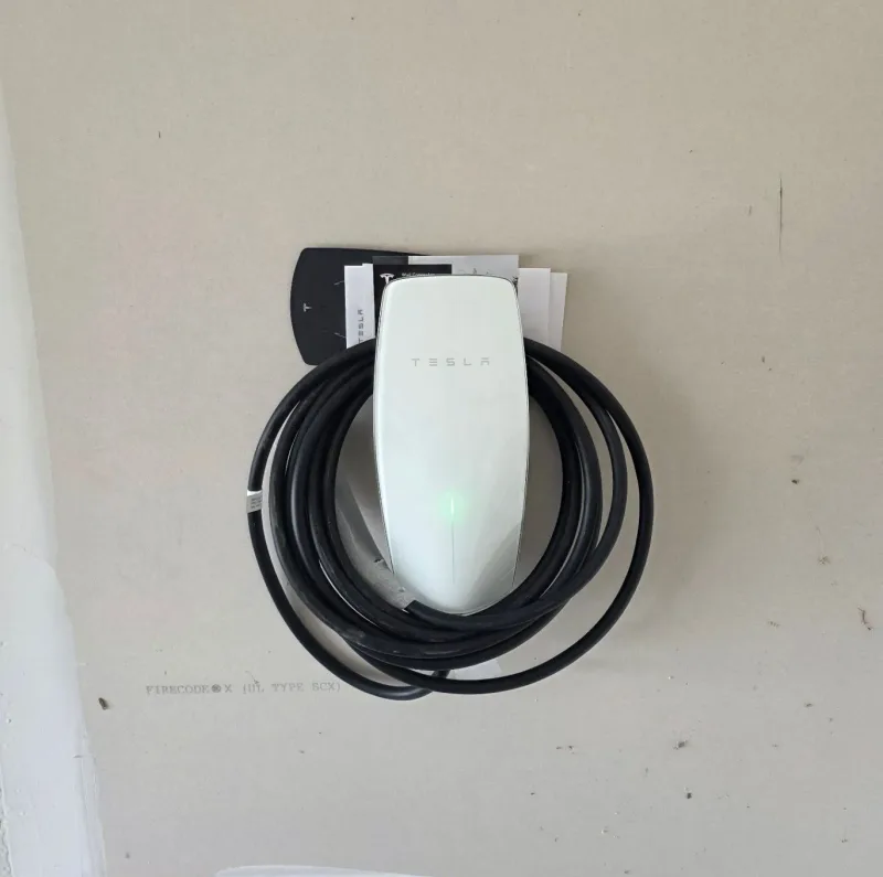 Tesla Wall Connector installed on a wall with the charging cable coiled